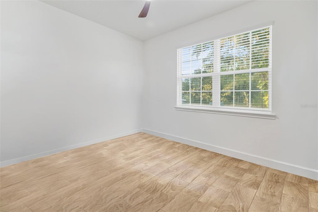 An empty room with white walls, light wood-look tile flooring, and a window with blinds — 4817 MILEY ROAD, PLANT CITY, FL