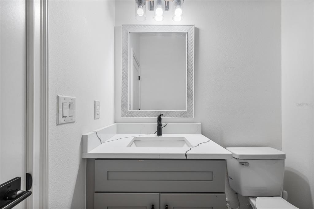 A bathroom features a gray vanity with a white marble countertop, a mirror, and toilet — 4817 MILEY ROAD, PLANT CITY, FL