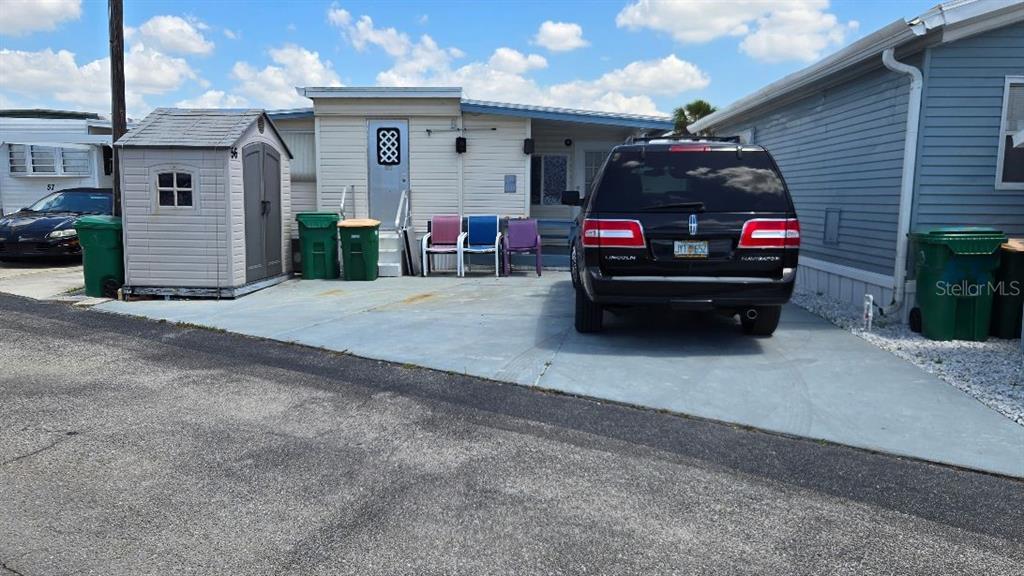 A mobile home exterior features a concrete driveway, a storage shed, and a parked SUV — 1475 FLAMINGO DRIVE UNIT 56, ENGLEWOOD, FL