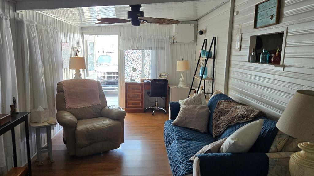 A living room features a recliner, a blue sofa, a desk, and wood-look flooring — 1475 FLAMINGO DRIVE UNIT 56, ENGLEWOOD, FL