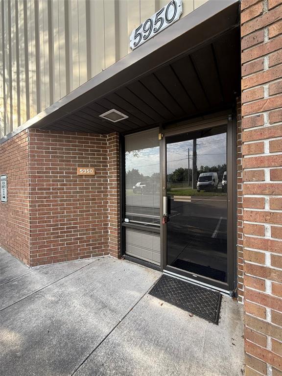 The exterior entrance of a commercial building features a glass door and brick walls — 5950 SW 1ST LANE, OCALA, FL