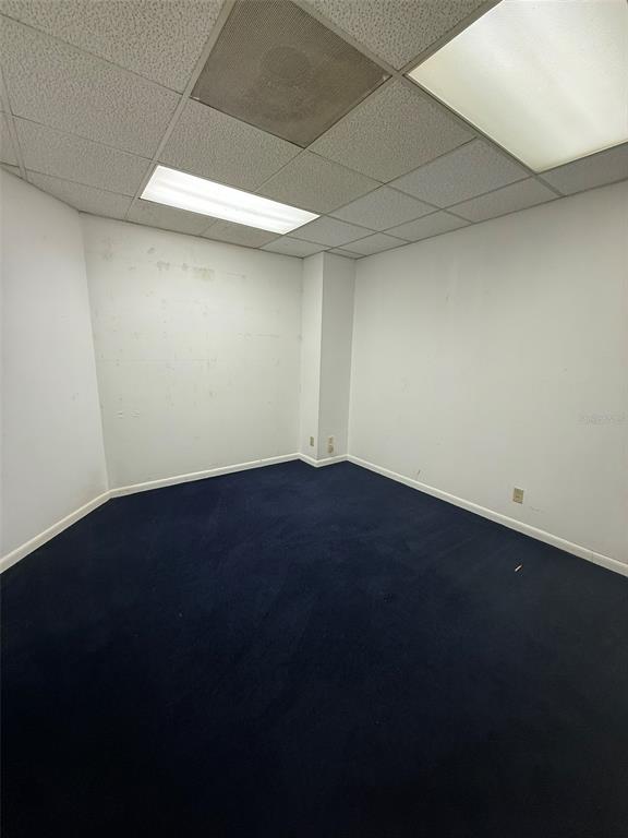 An empty office room features white walls, a dark blue carpet, and a drop ceiling — 5950 SW 1ST LANE, OCALA, FL