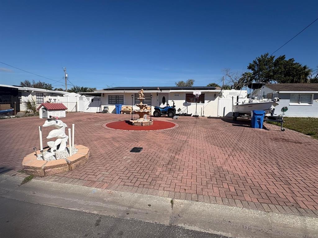 A single-story house with a large brick-paved driveway, a central fountain, and a boat trailer — 6005 W CLIFTON STREET, TAMPA, FL