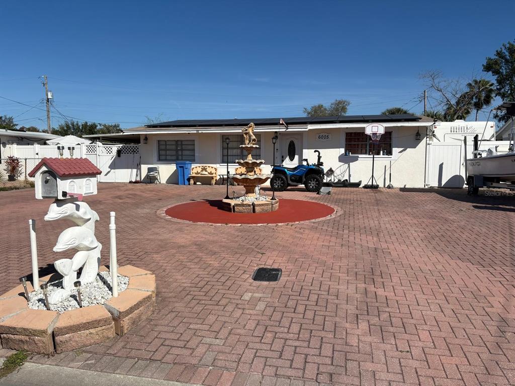 A single-story house with a paved driveway, a central fountain, and a dolphin-themed mailbox — 6005 W CLIFTON STREET, TAMPA, FL