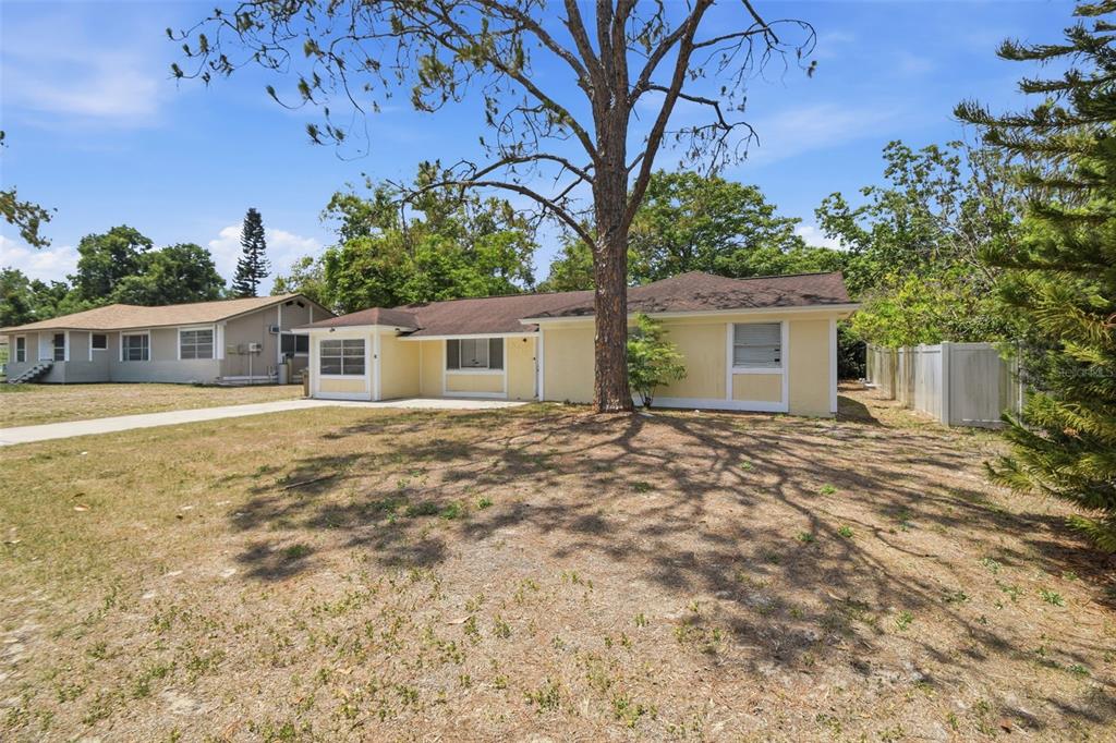 A single-story yellow house with a brown roof sits on a grassy lot — 8412 RENALD BOULEVARD, TAMPA, FL