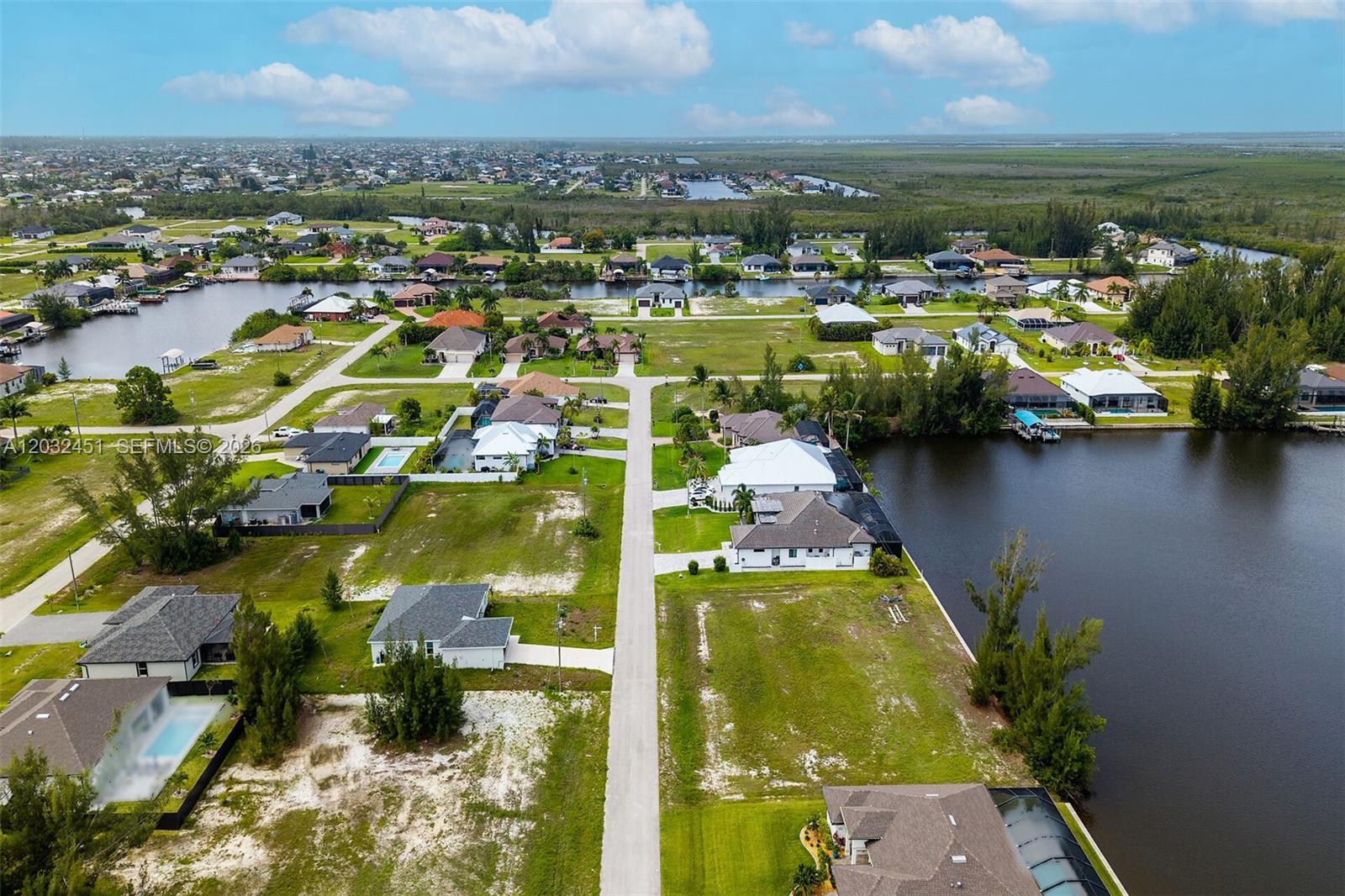 An aerial view shows a suburban neighborhood with houses, vacant lots, and canals — 2221 NW 43rd, Cape Coral FL 33993, CAPE CORAL, FL