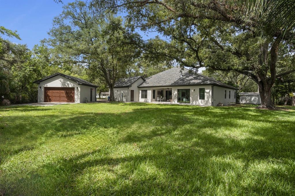 A single-story house with a detached garage sits on a large, tree-shaded grassy lawn — 3006 S EMERSON STREET, TAMPA, FL
