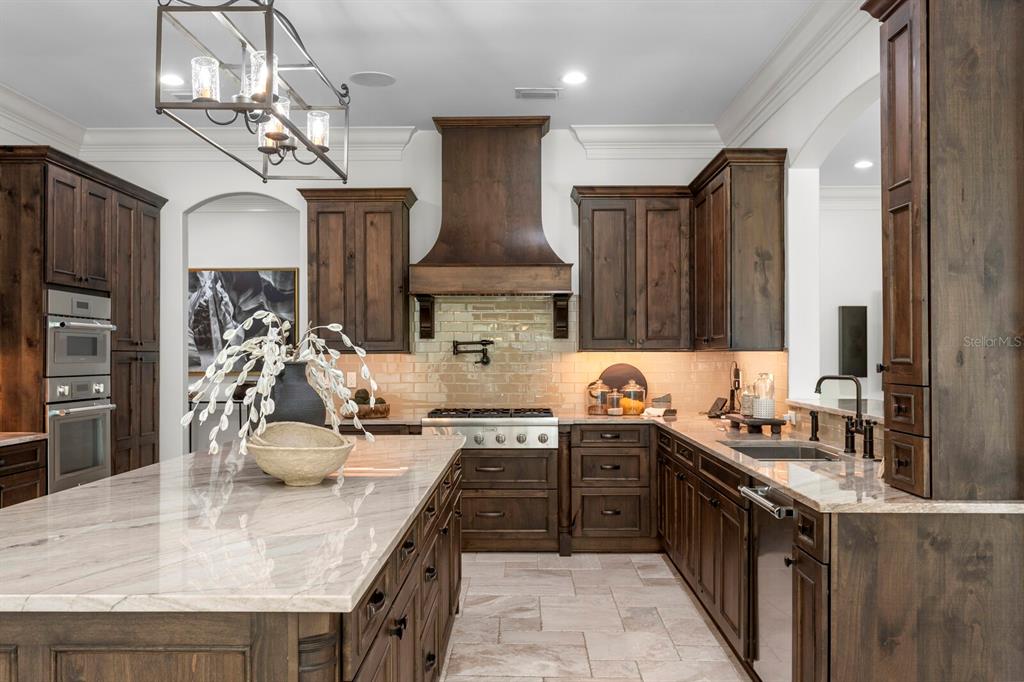 A kitchen features dark wood cabinetry, a large stone-topped island, and a stainless steel range — 3006 S EMERSON STREET, TAMPA, FL