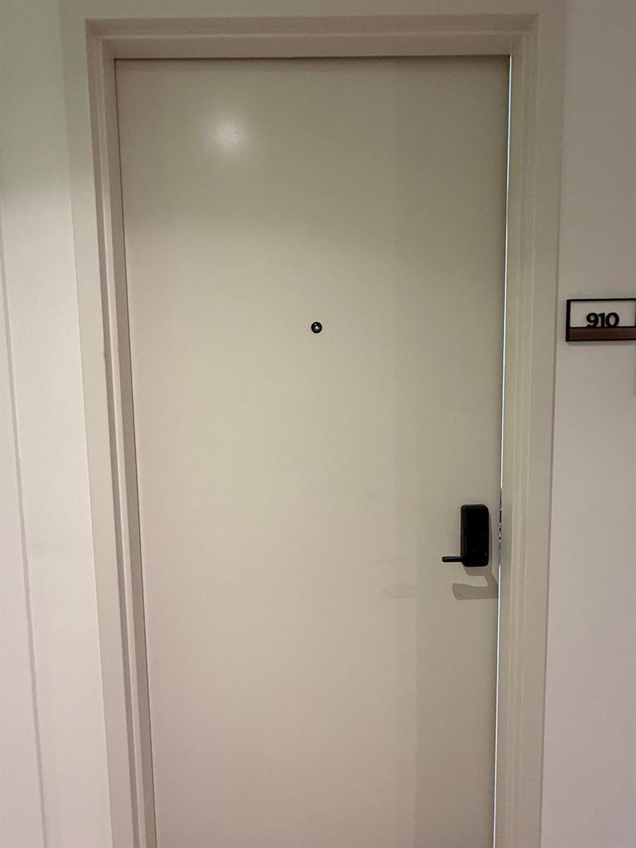 A white door with a peephole and electronic lock is labeled with the number 910 — 225 N Miami Avenue # 910, Miami FL 33128, MIAMI, FL