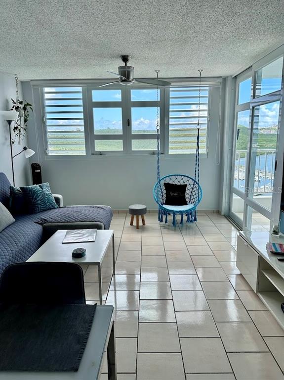 A sunroom features tile flooring, a hanging chair, and large windows overlooking a marina — 200 MARINA VIEW DOS MARINAS II CONDOMINIUM UNIT 2103, FAJARDO, PR