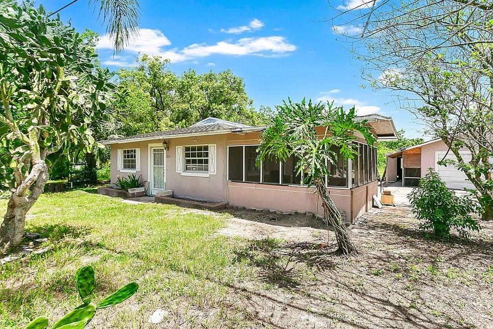 A single-story house with a screened-in porch, tan siding, and a large cactus in front — 2110 JAMES DRIVE, OVIEDO, FL