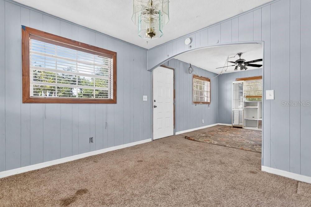A living room with light blue wood-paneled walls, brown carpeting, and an arched entryway — 2110 JAMES DRIVE, OVIEDO, FL