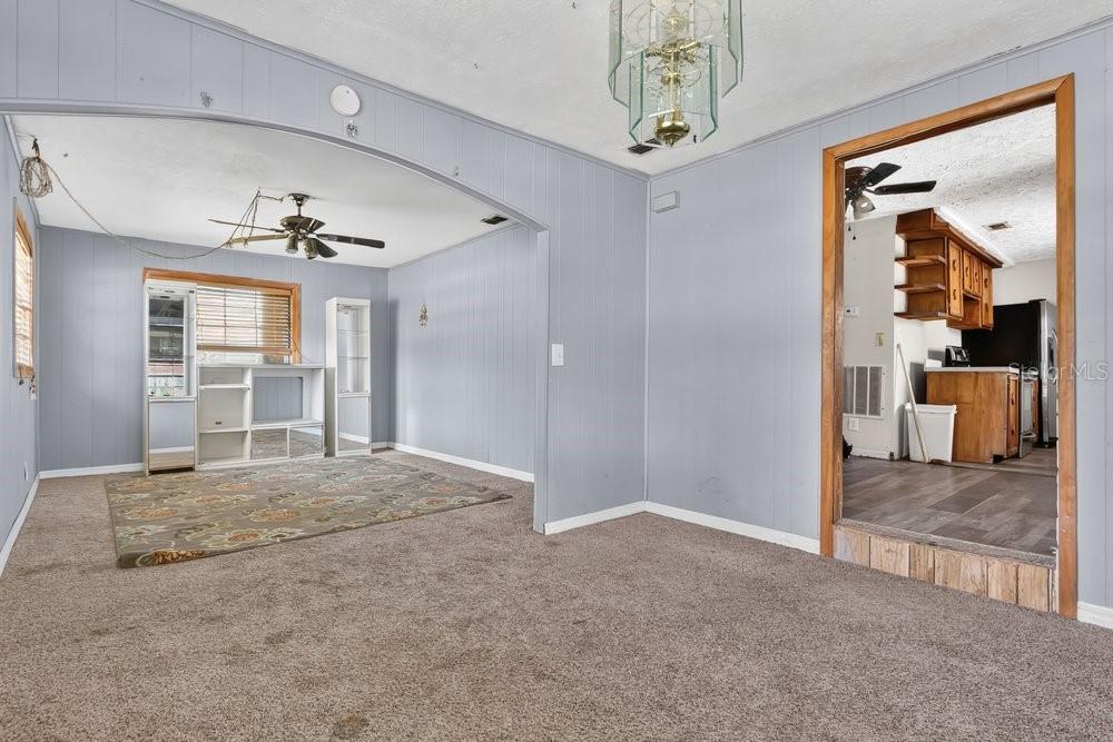 A carpeted living room with light blue paneled walls leads into a kitchen area — 2110 JAMES DRIVE, OVIEDO, FL