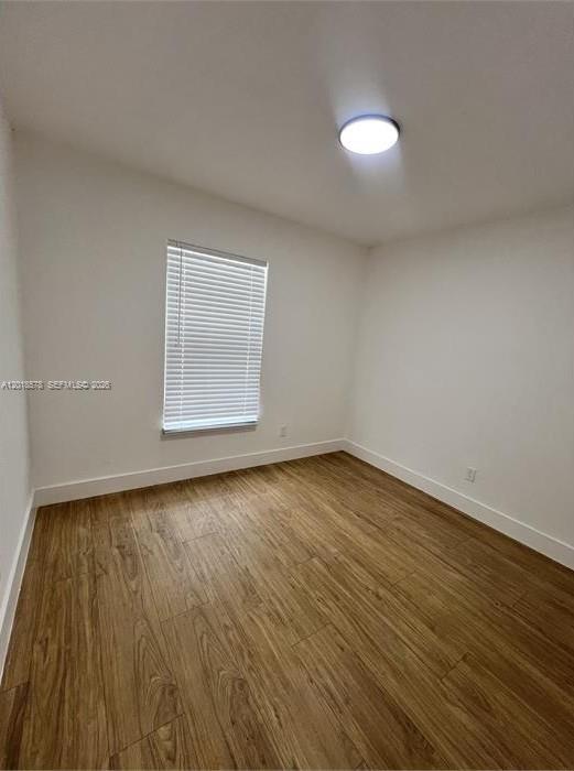 An empty room features white walls, a single window with blinds, and wood-look flooring — 201-205 NW 30th Ave, Pompano Beach FL 33069, POMPANO BEACH, FL