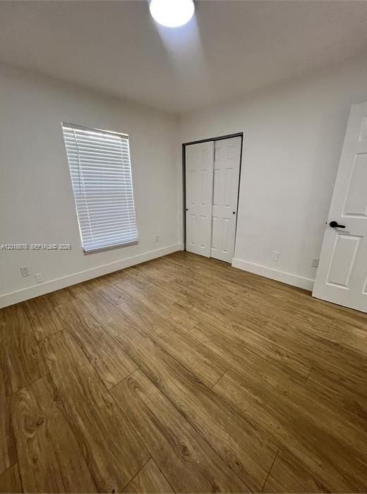 An empty bedroom features white walls, wood-look tile flooring, a window with blinds, and closets — 201-205 NW 30th Ave, Pompano Beach FL 33069, POMPANO BEACH, FL