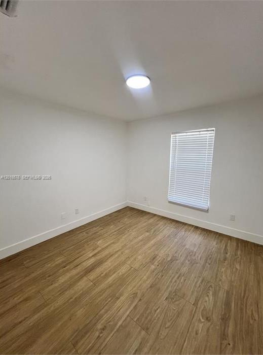 An empty room features white walls, a single window with blinds, and wood-look flooring — 201-205 NW 30th Ave, Pompano Beach FL 33069, POMPANO BEACH, FL