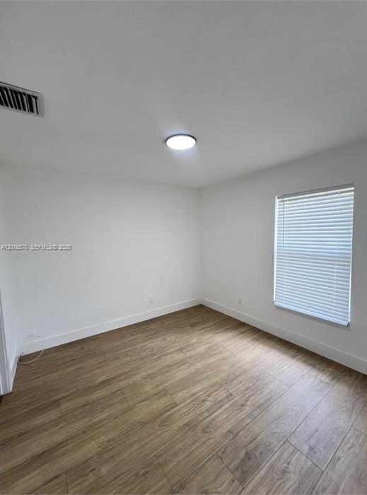 An empty bedroom features light wood-look flooring, white walls, a ceiling light, and a window — 201-205 NW 30th Ave, Pompano Beach FL 33069, POMPANO BEACH, FL