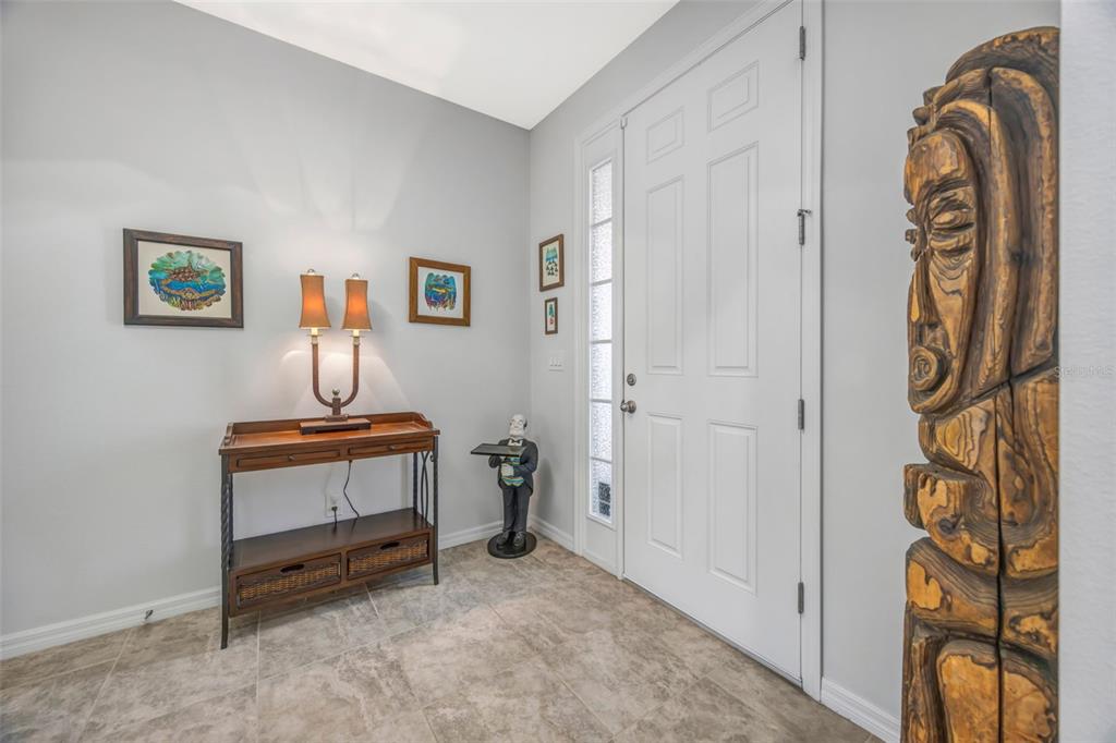 An entryway features tile flooring, a wooden console table with a lamp, and a carved statue — 5652 FISHER GLEN LOOP, WESLEY CHAPEL, FL