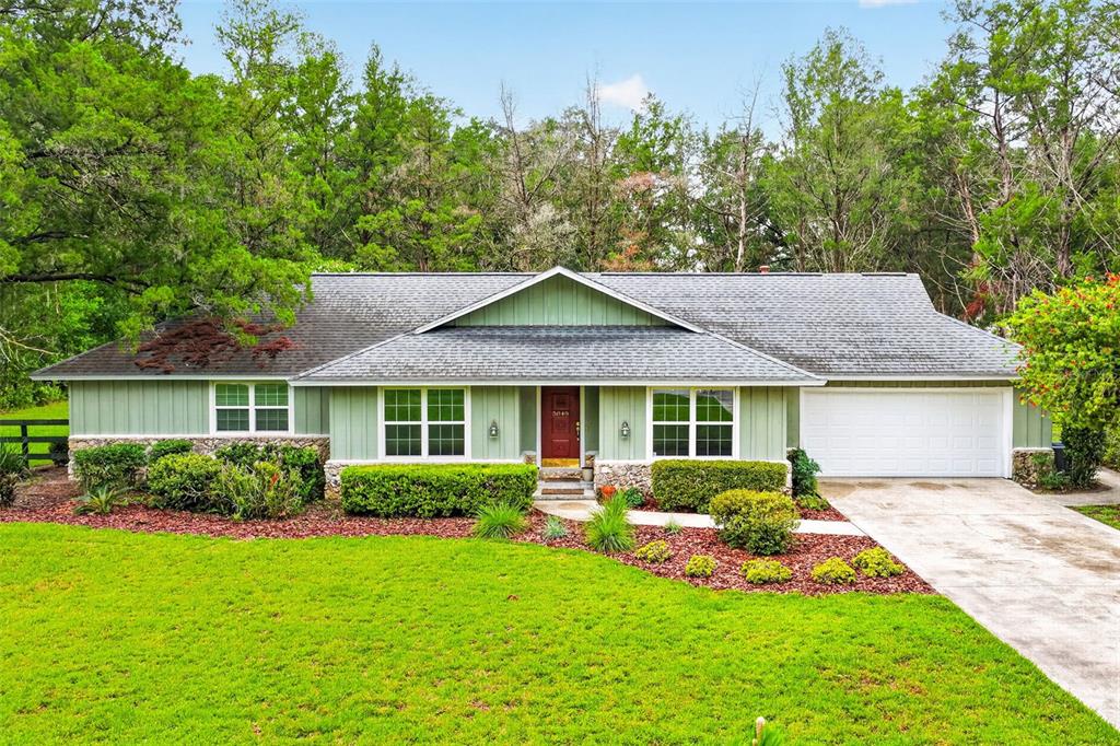 A single-story house with green vertical siding, a red front door, and a two-car garage — 5040 SE 18TH STREET, OCALA, FL