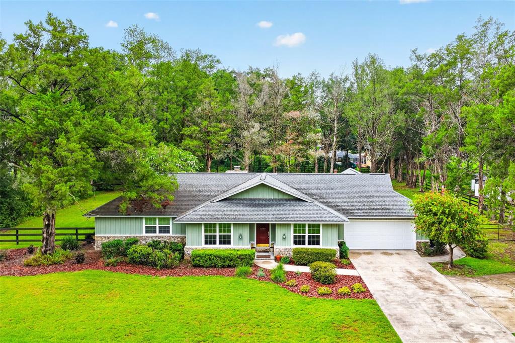 A single-story house with green siding, a stone base, and a two-car garage — 5040 SE 18TH STREET, OCALA, FL