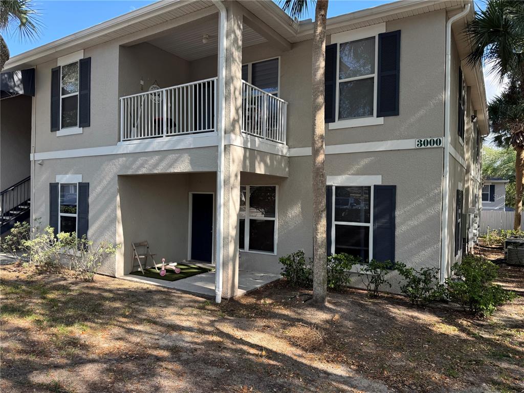A two-story apartment building with a balcony, ground-level patio, and dark blue shutters — 3011 HEMINGWAY CIRCLE UNIT 3011, HAINES CITY, FL