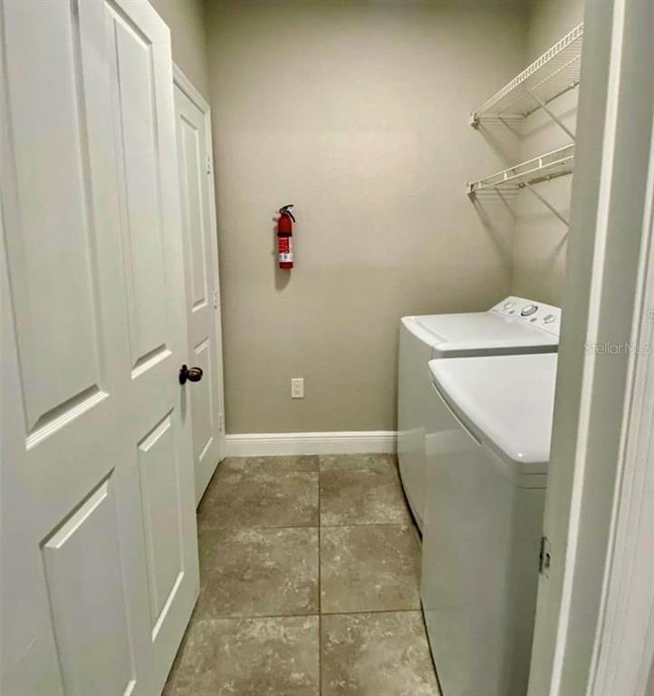 A laundry room features tile flooring, white appliances, and wall-mounted wire shelving — 3011 HEMINGWAY CIRCLE UNIT 3011, HAINES CITY, FL