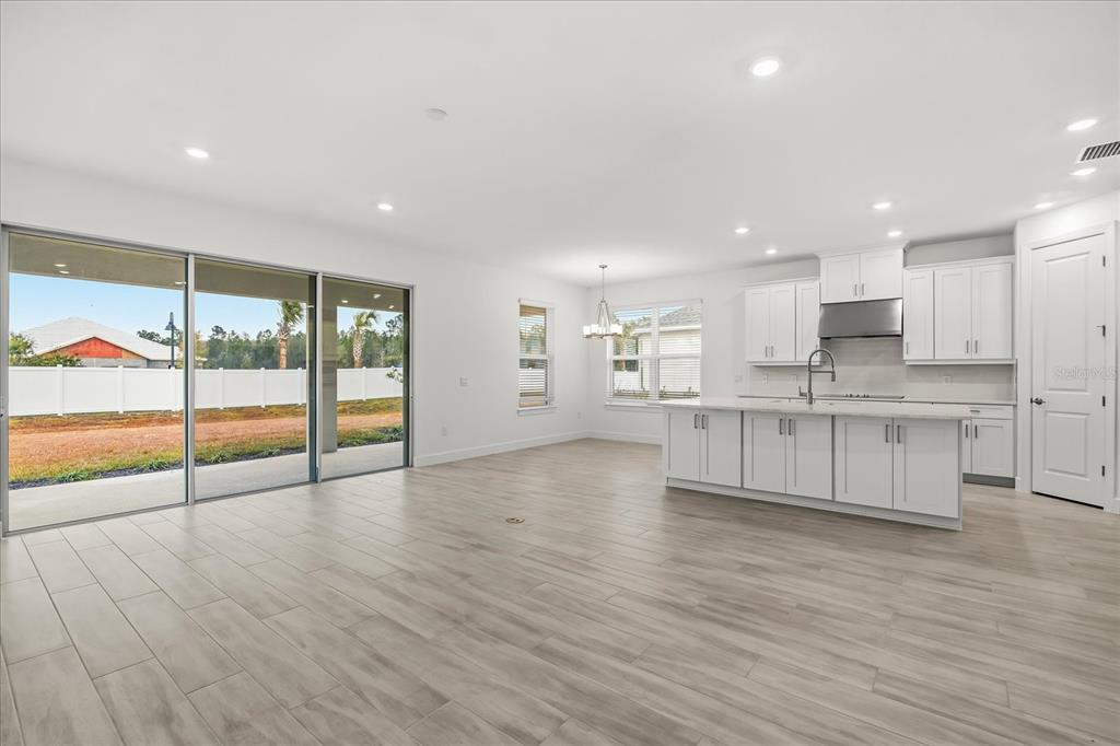 A bright, open-concept kitchen and living area features white cabinetry, a large island, and tile flooring — 4240 BARBUDA LANE, KISSIMMEE, FL