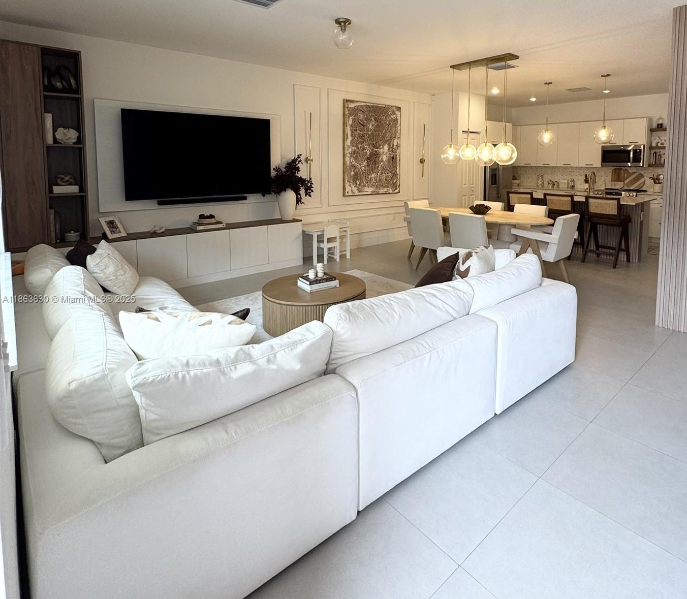 A bright, open-concept living and dining area features a large white sectional and modern decor — 4867 NW 84th Ave, Doral FL 33166, DORAL, FL