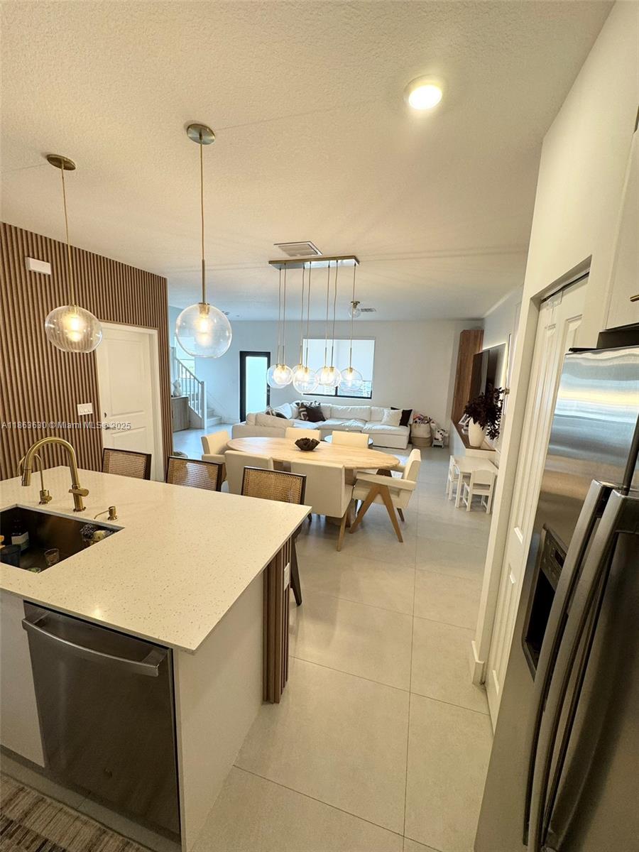 A modern kitchen with a white island overlooks an open-concept dining and living area — 4867 NW 84th Ave, Doral FL 33166, DORAL, FL