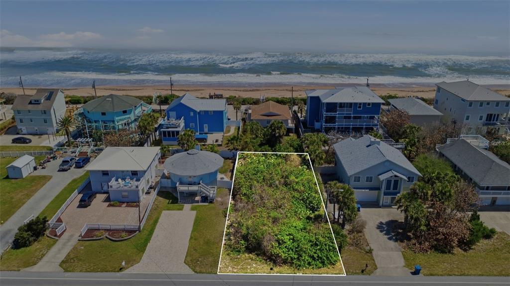 An aerial view shows a vacant, rectangular lot situated between two houses near the ocean — 6355 TURTLEMOUND ROAD, NEW SMYRNA BEACH, FL