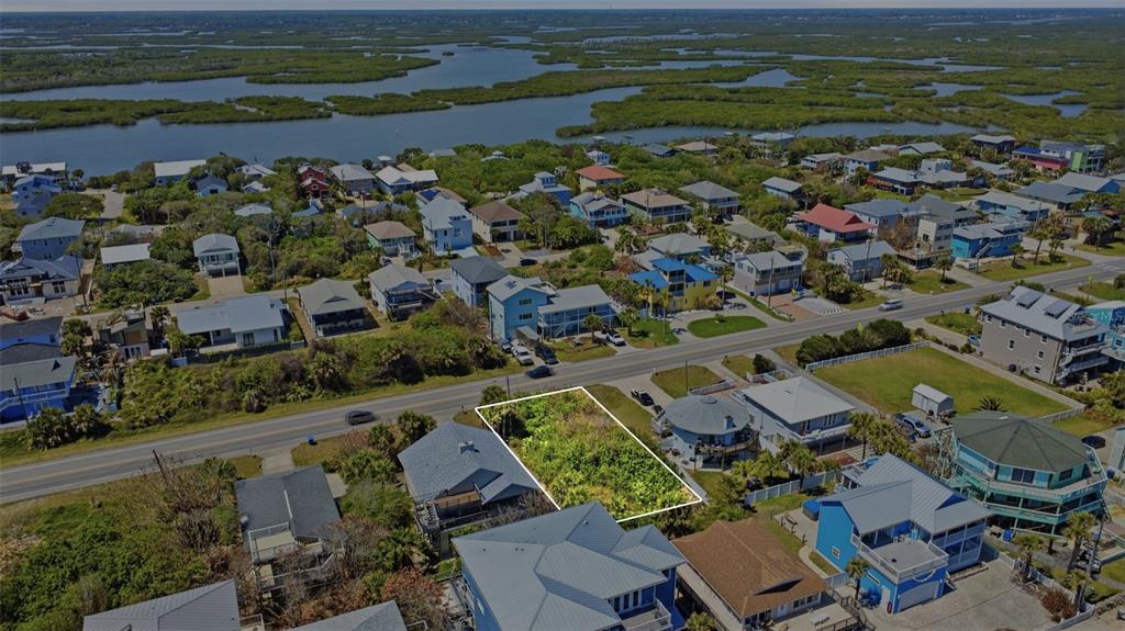 An aerial view shows a vacant, rectangular lot situated between two houses near a road — 6355 TURTLEMOUND ROAD, NEW SMYRNA BEACH, FL