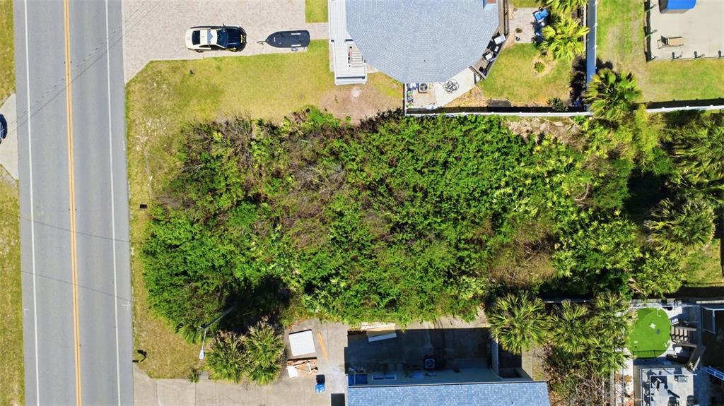 An aerial view shows a rectangular, overgrown vacant lot situated between two residential properties — 6355 TURTLEMOUND ROAD, NEW SMYRNA BEACH, FL