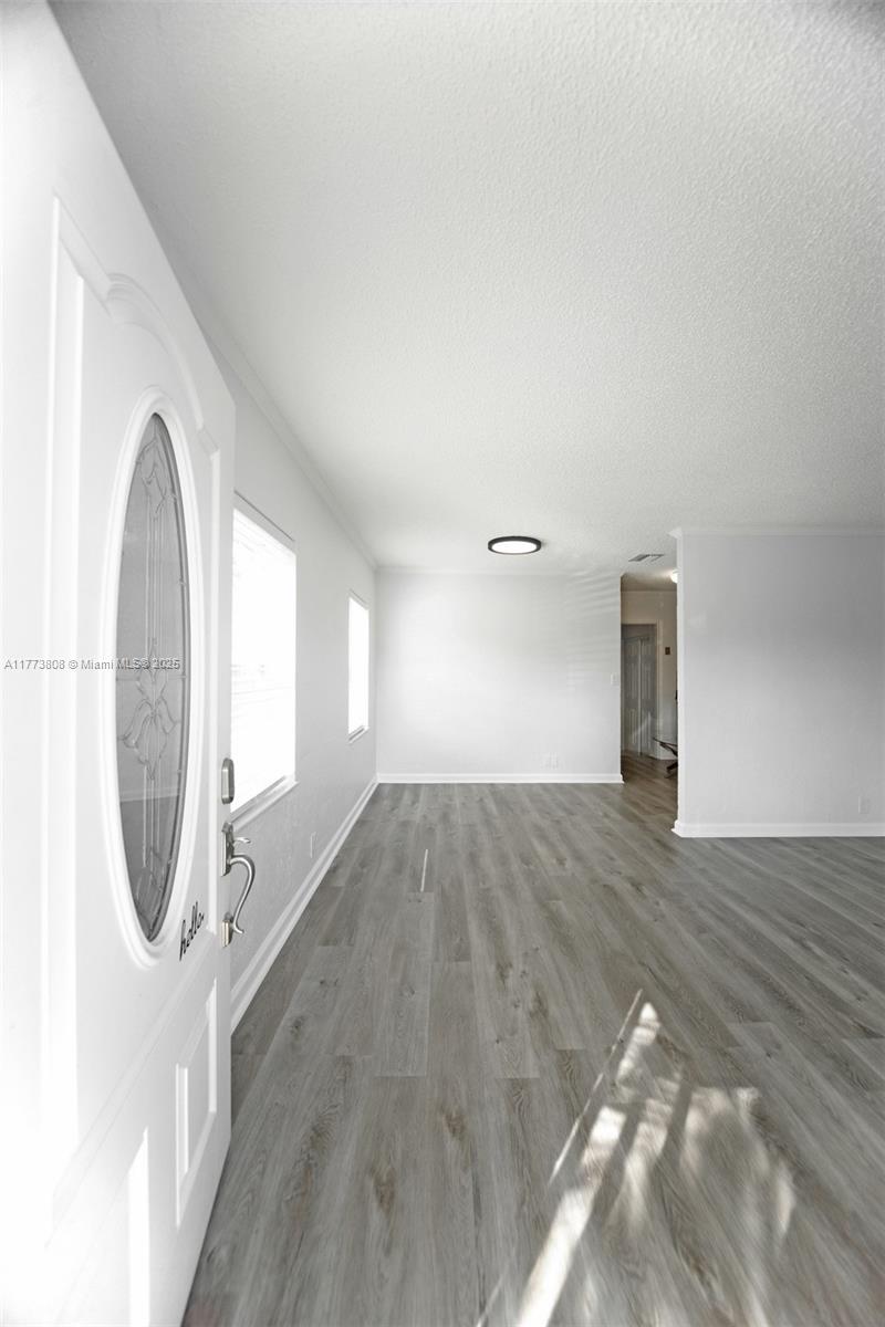 An entryway leads into a bright living area with gray wood-look flooring and white walls — 621 Hudson Rd, West Palm Beach FL 33405, WEST PALM BEACH, FL