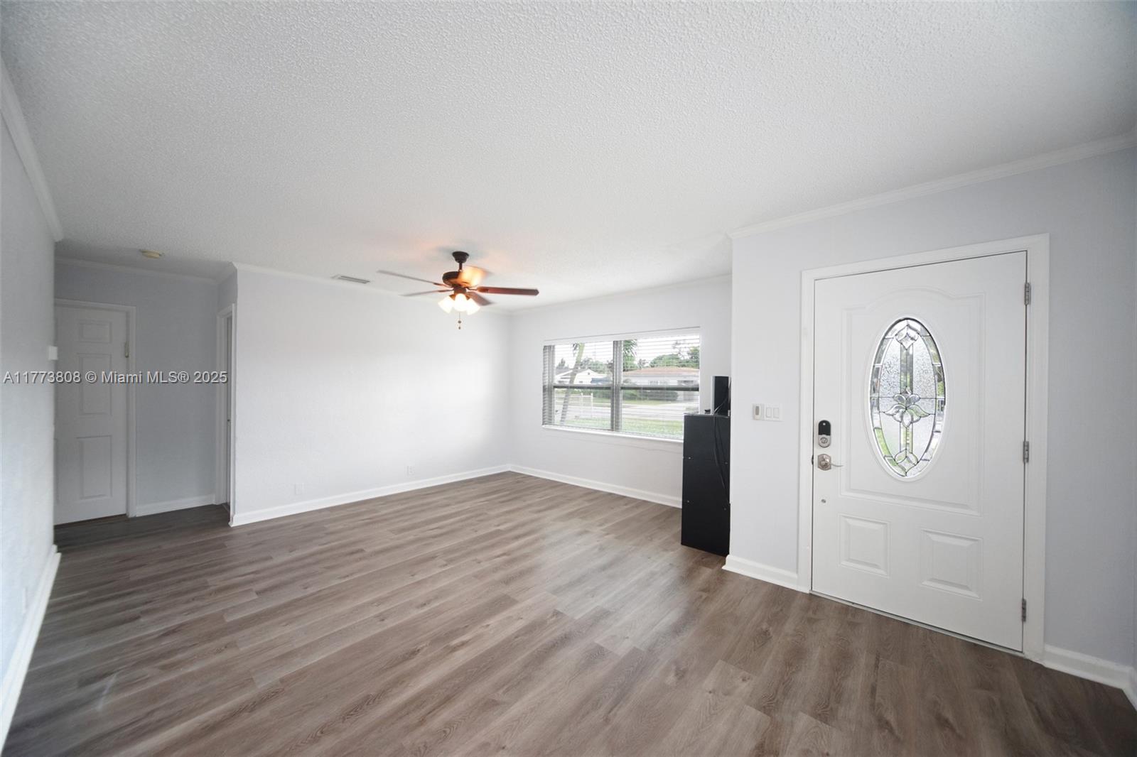This living room features light gray walls, wood-look flooring, a ceiling fan, and a front door — 621 Hudson Rd, West Palm Beach FL 33405, WEST PALM BEACH, FL