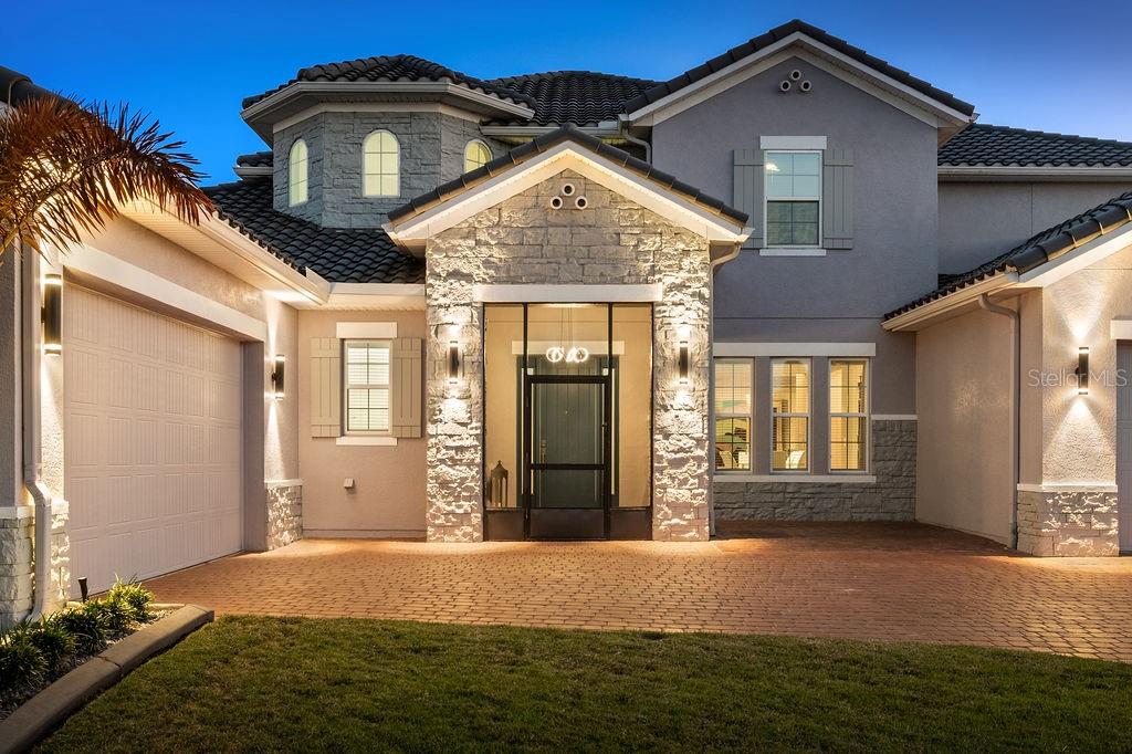 A two-story house exterior features a stone-accented entryway, a brick driveway, and a garage — 840 SPINNAKER WAY, KISSIMMEE, FL