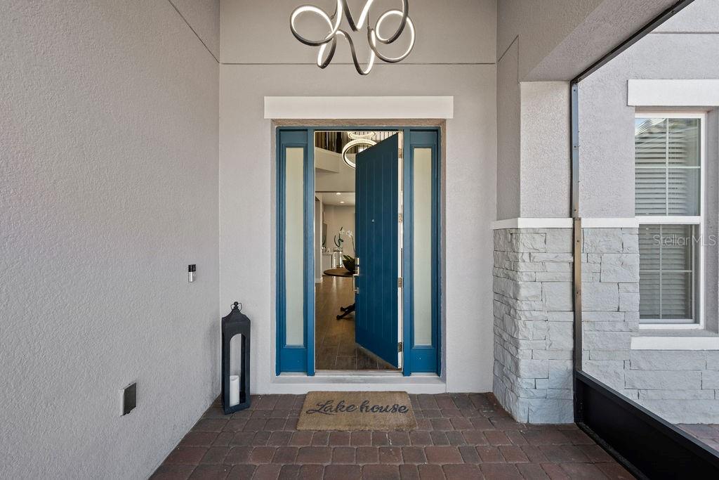 A blue front door with sidelights opens to an interior entryway with a stone-accented exterior — 840 SPINNAKER WAY, KISSIMMEE, FL