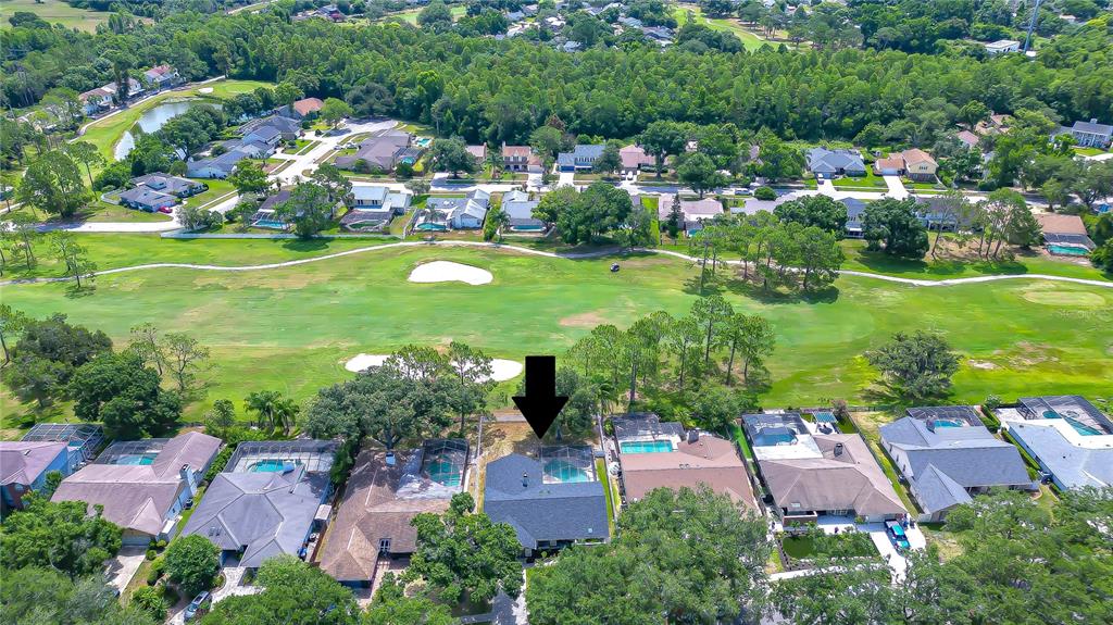 An aerial view shows a residential house with a pool overlooking a golf course — 16605 E COURSE DRIVE, TAMPA, FL