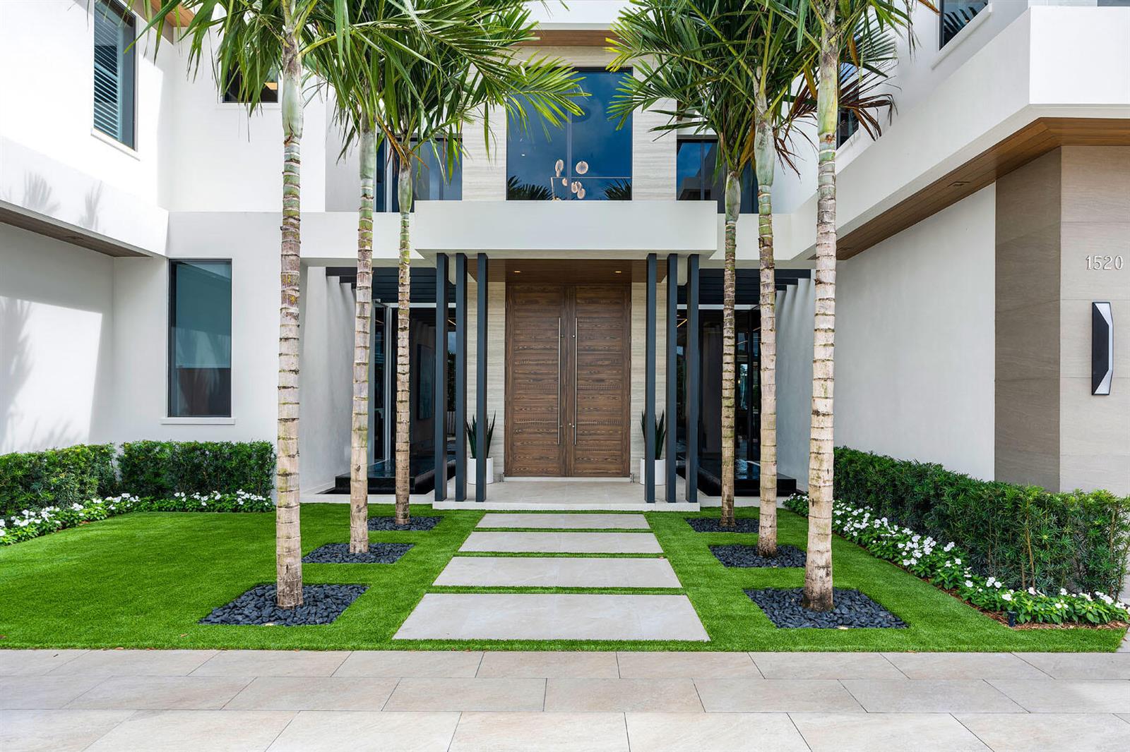 The exterior of a modern home features a wooden double door, palm trees, and landscaping — 1520 Royal Palm Way, Boca Raton FL 33432, BOCA RATON, FL