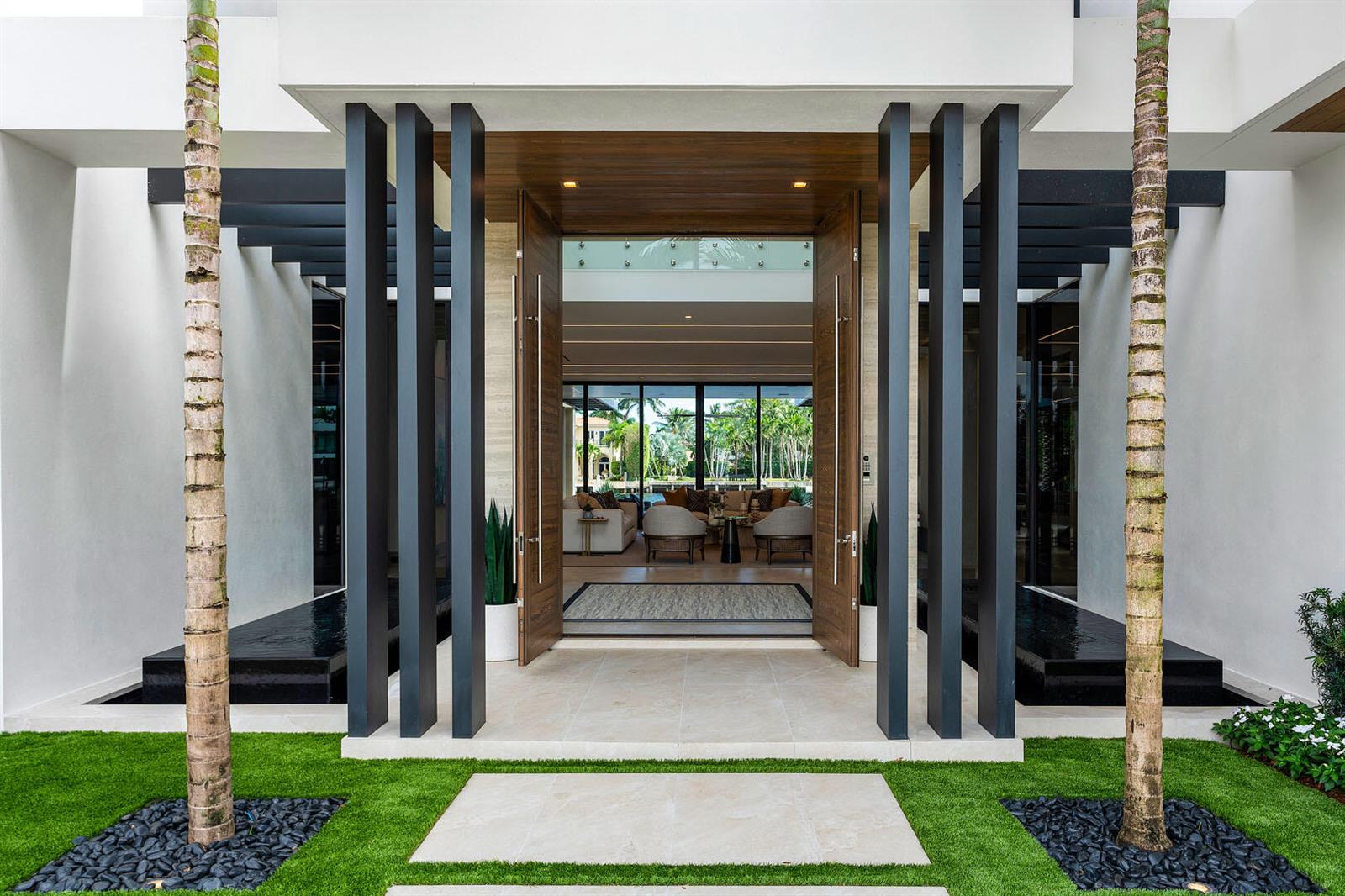 A modern home entrance features a wooden double door, vertical black pillars, and palm trees — 1520 Royal Palm Way, Boca Raton FL 33432, BOCA RATON, FL