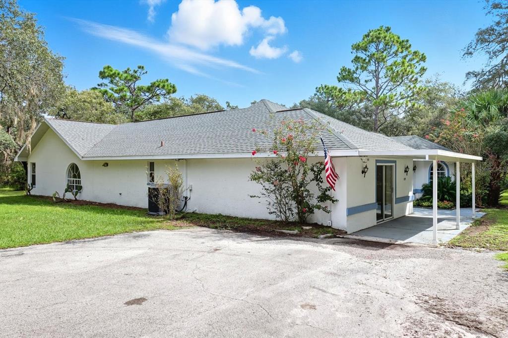A single-story white house with a gray shingled roof and a covered concrete patio area — 4355 W JUSTICE COURT, HOMOSASSA, FL