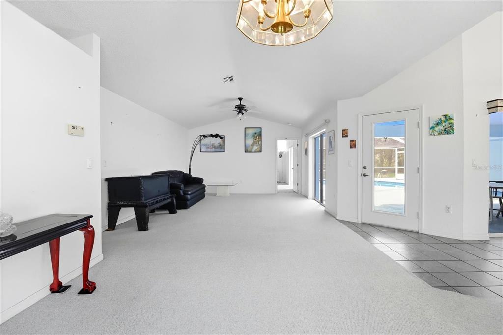 A spacious living room features white walls, light carpeting, a vaulted ceiling, and a glass door — 4355 W JUSTICE COURT, HOMOSASSA, FL