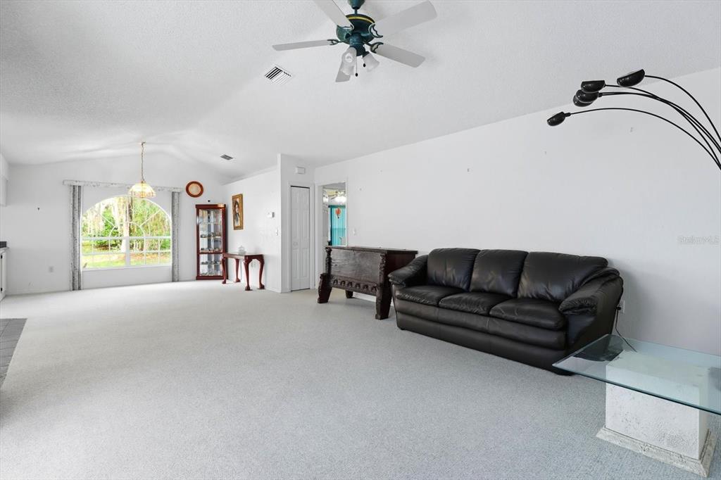 A living room features a black leather sofa, white carpeting, and a ceiling fan — 4355 W JUSTICE COURT, HOMOSASSA, FL