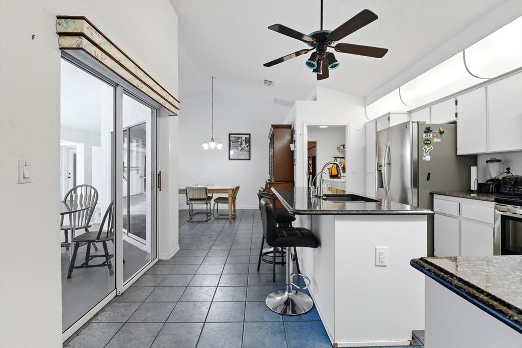 A kitchen with a granite island, dark tile floors, and an adjacent dining area — 4355 W JUSTICE COURT, HOMOSASSA, FL