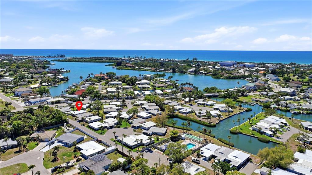 This aerial view shows a residential neighborhood with canals and a distant ocean coastline — 215 FAIR WINDS DRIVE UNIT 215, NOKOMIS, FL