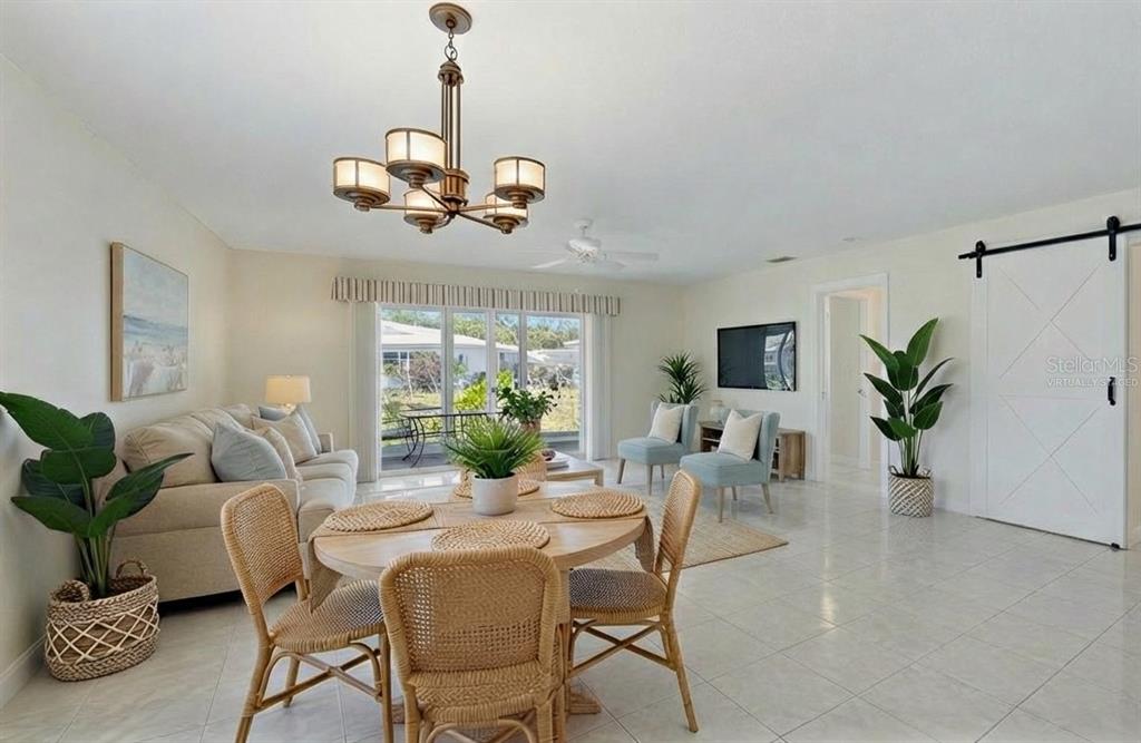 A living and dining area features tile floors, a chandelier, and a sliding barn door — 215 FAIR WINDS DRIVE UNIT 215, NOKOMIS, FL
