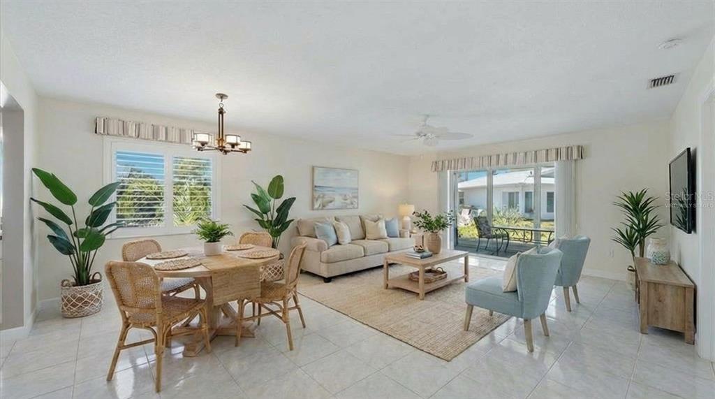 A bright living and dining room with tile floors, a beige sofa, and sliding glass doors — 215 FAIR WINDS DRIVE UNIT 215, NOKOMIS, FL