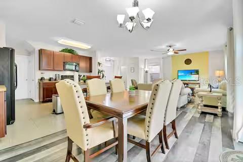 A dining area with a wooden table and chairs opens into a kitchen and living room — 10108 HAWK STORM AVENUE, TAMPA, FL