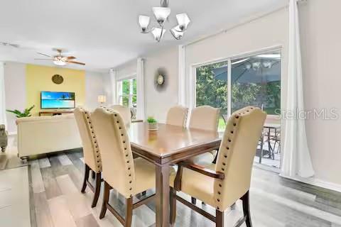 A dining area with a wooden table, upholstered chairs, and a chandelier near sliding doors — 10108 HAWK STORM AVENUE, TAMPA, FL