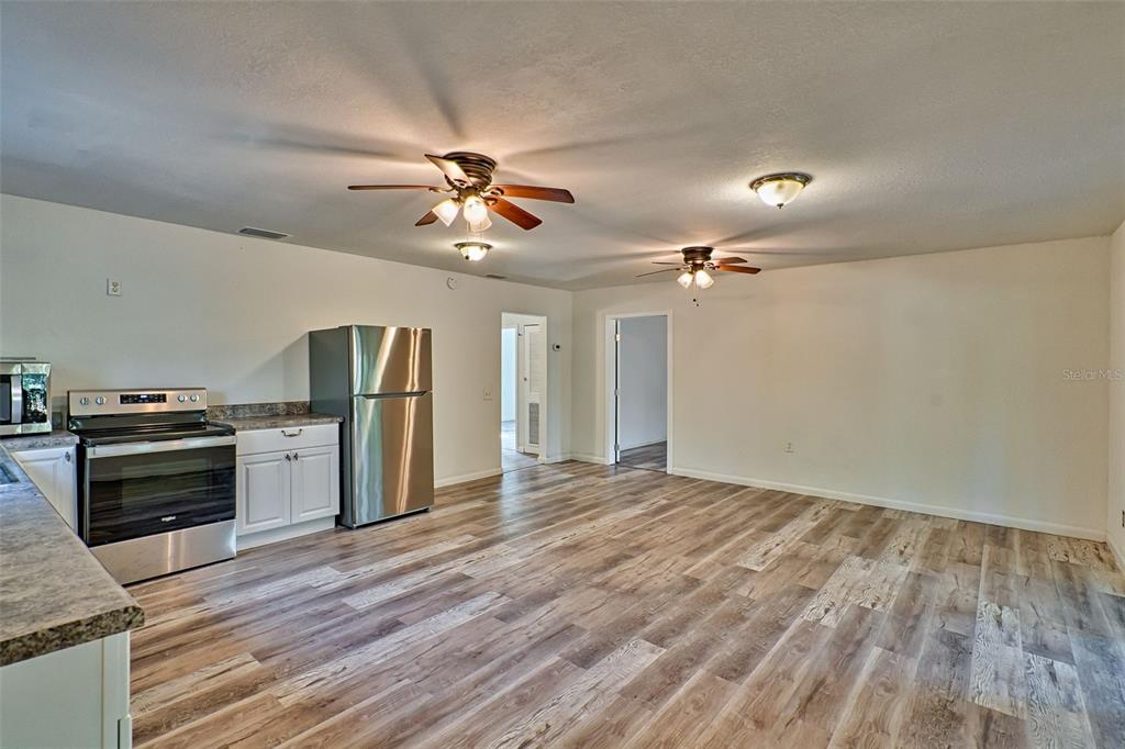 A kitchen and living area with wood-look flooring, stainless steel appliances, and two ceiling fans — 300 S US HIGHWAY 129, BELL, FL