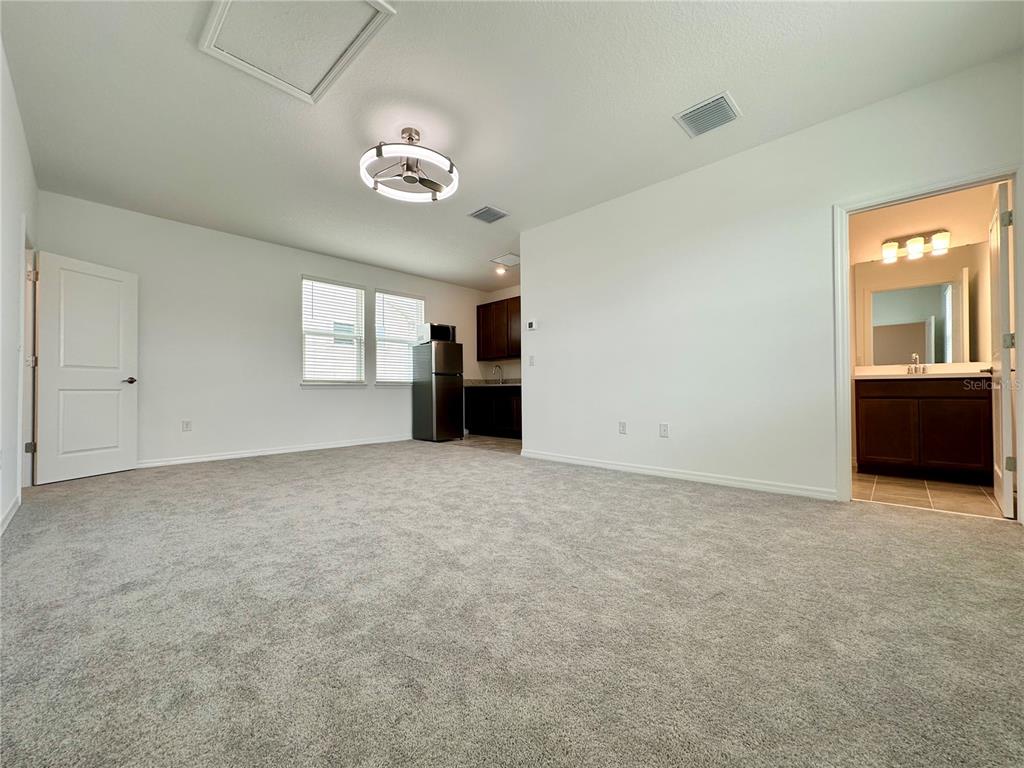 A carpeted room features a small kitchenette, a ceiling fan, and an attached bathroom — 12761 HARVEST RAIN AVENUE, WINTER GARDEN, FL